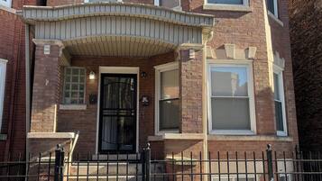 A corner brick building with a bay window, a front door, and a small porch.