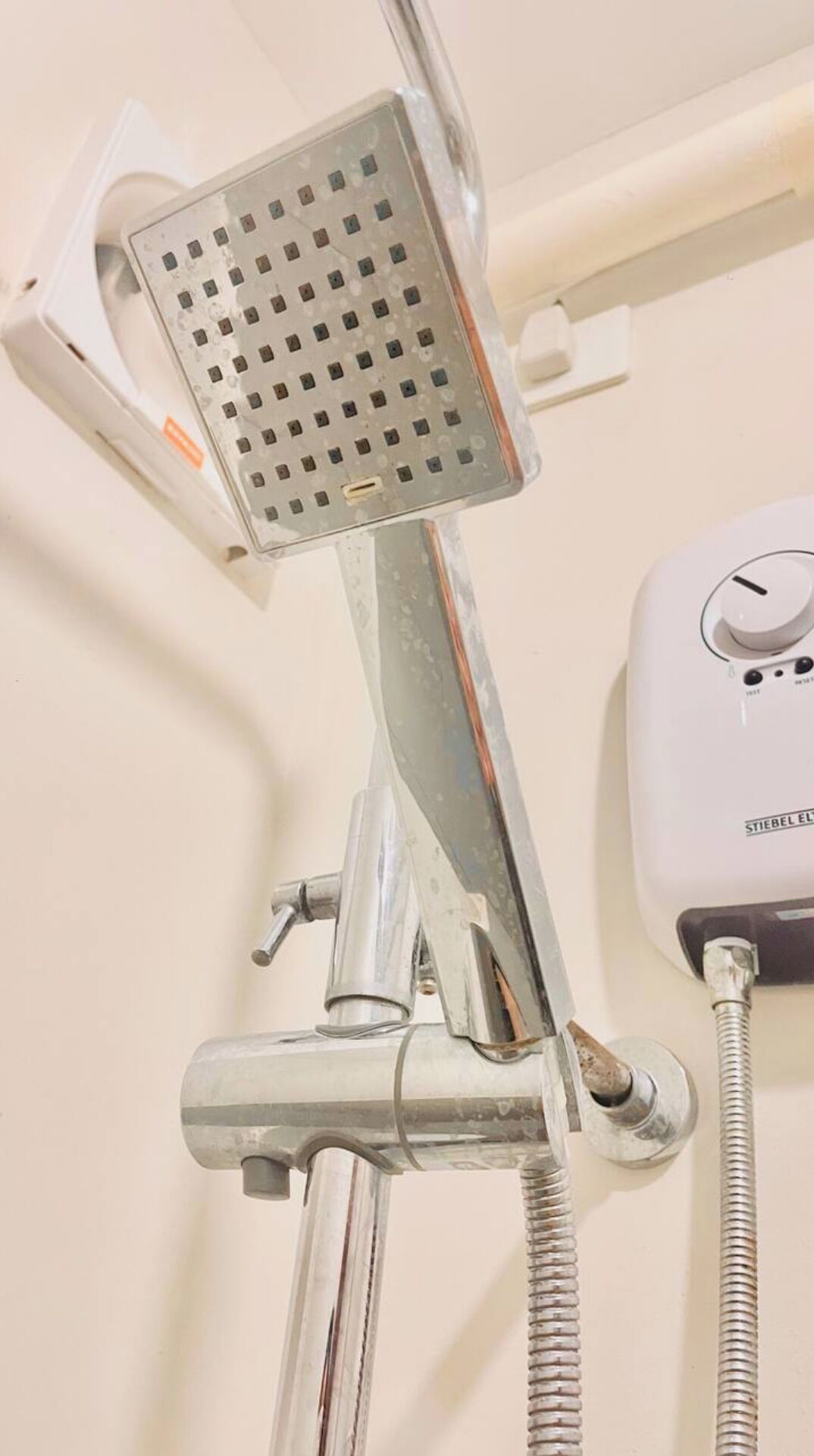 A showerhead with a control panel, a flexible hose, and a metal pipe.