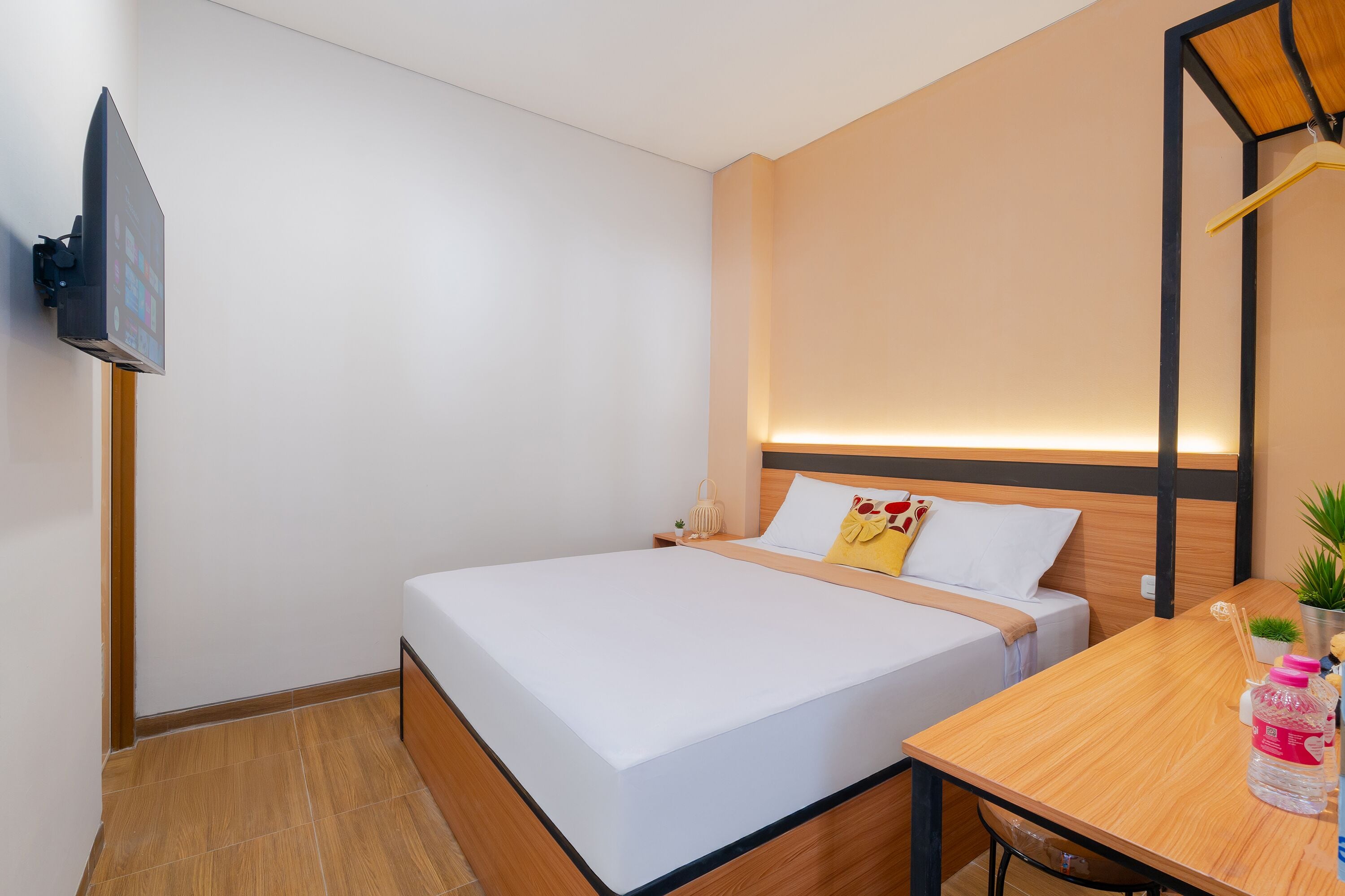 A modern hotel room with a bed, bedside table, and a TV mounted on the wall.