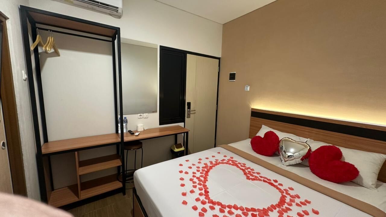 A hotel room with a bed, a desk, a mirror, and a wardrobe.