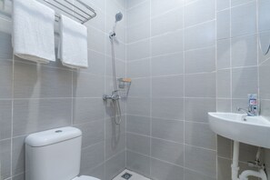 A modern bathroom with grey tiles, a white sink, and a shower.