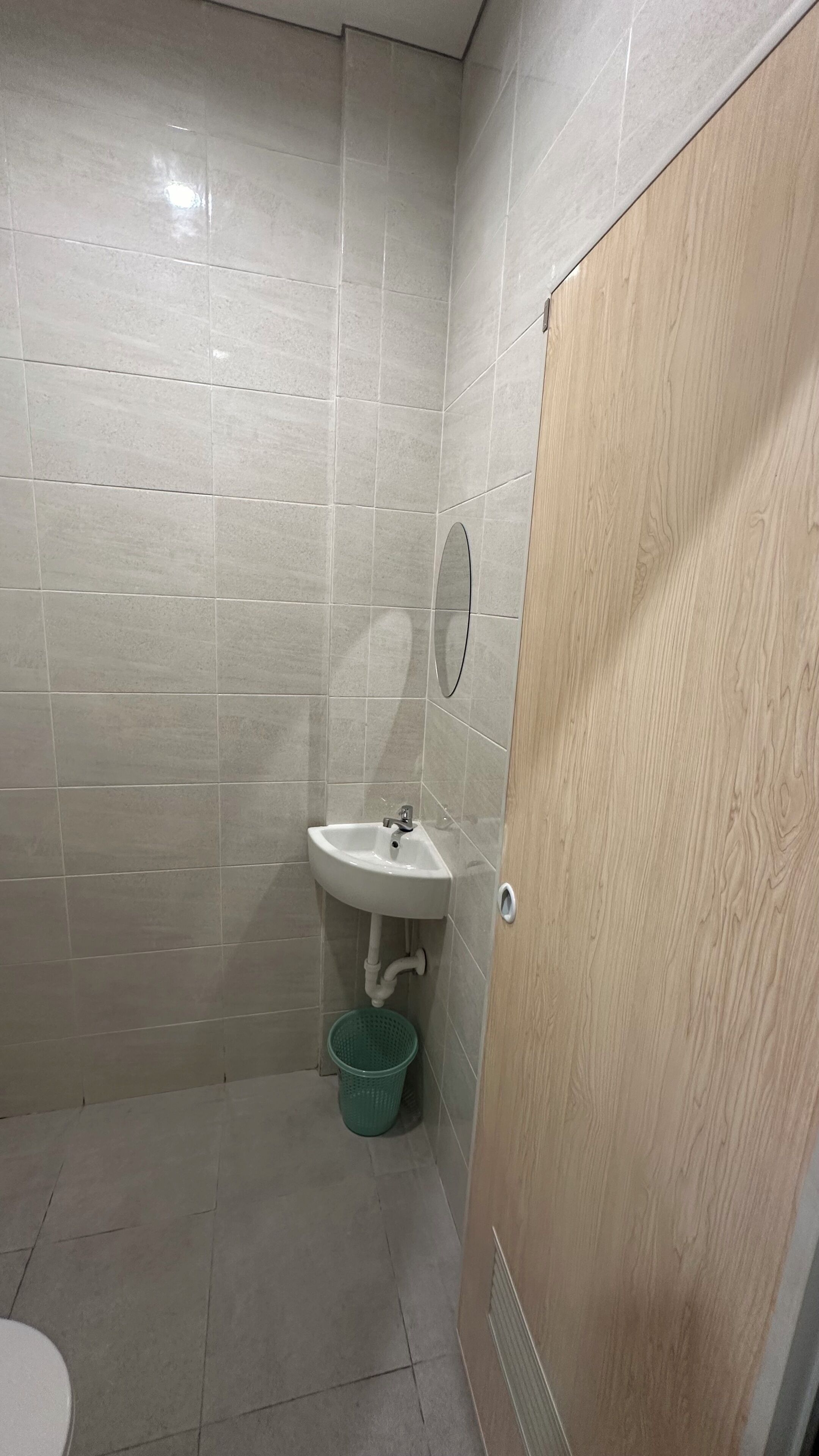 Casa de banho pequena com lavatório, espelho e porta de madeira.