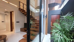 Un interior moderno con una escalera, un separador de vidrio y una planta en maceta.