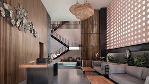 Un interior moderno con un mostrador de recepción de madera, una escalera, un área de descanso y una pared decorativa con diseños circulares.