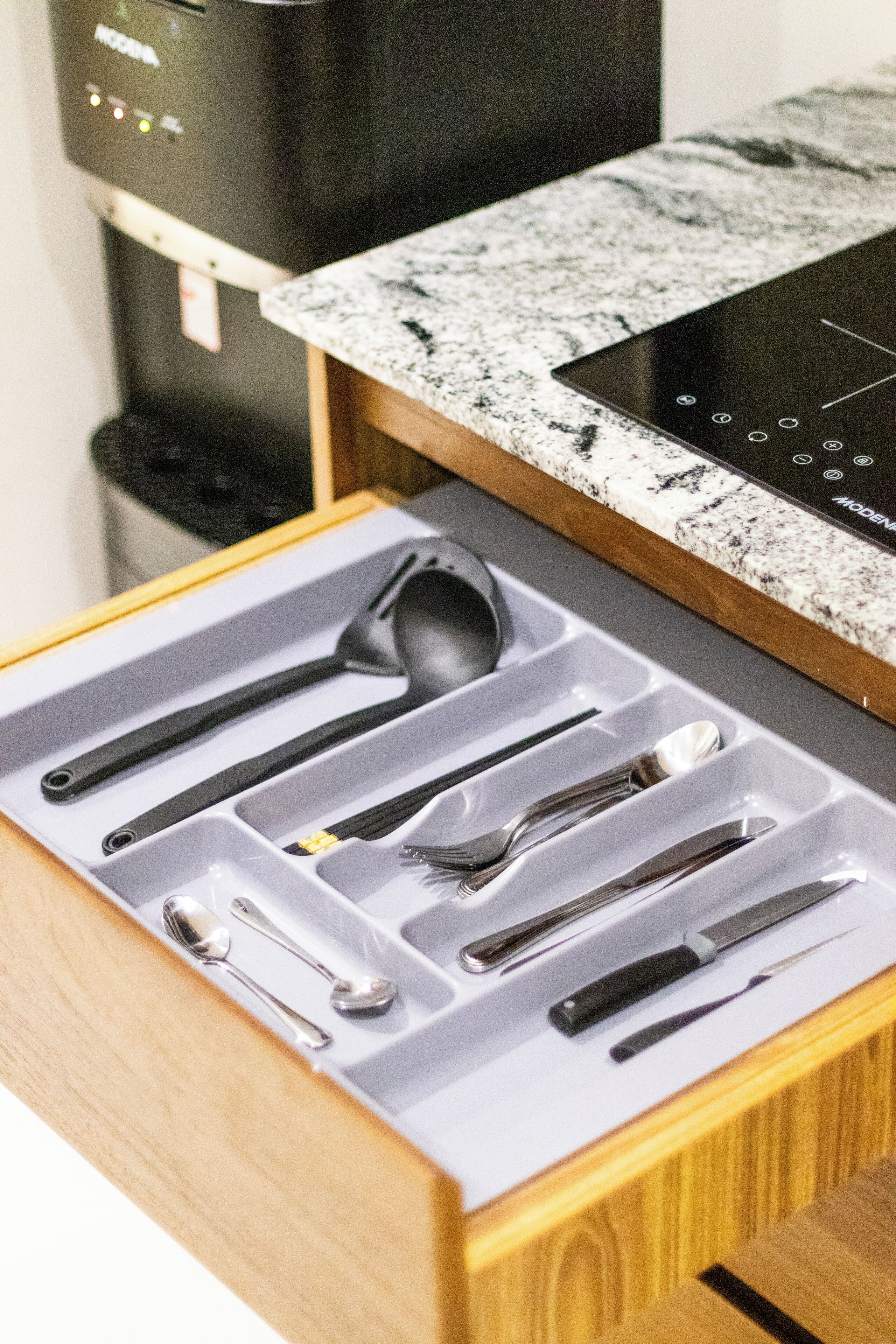 A drawer with a set of kitchen utensils including spoons, forks, and knives.