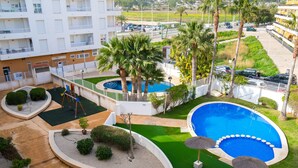 A pool area with a circular pool, palm trees, and a building in the background. - Cala Mora by Interhome (Moraira)
