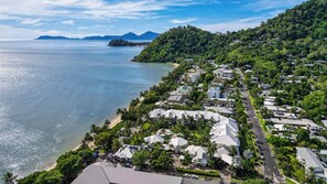 A coastal resort with multiple white-roofed buildings, a beachfront, and lush greenery.