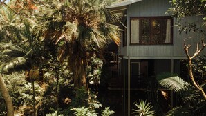 Una casa de dos pisos rodeada de exuberante vegetación tropical.