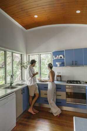 A modern kitchen with wooden flooring, a gas stove, and blue cabinets.