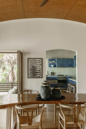 A dining area with a wooden table and chairs, a large vase, and a framed fish illustration on the wall.