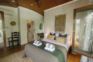 A bedroom with a bed, a chair, a desk, and a mirror.