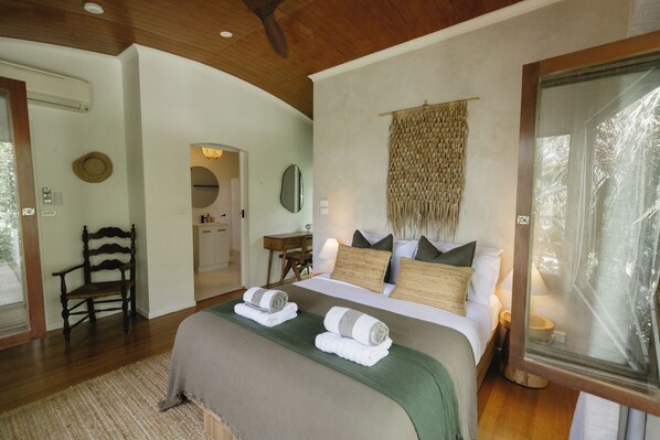 A bedroom with a bed, a chair, a desk, and a mirror.