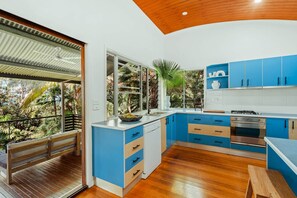A modern kitchen with blue cabinets, a white countertop, and a wooden ceiling.