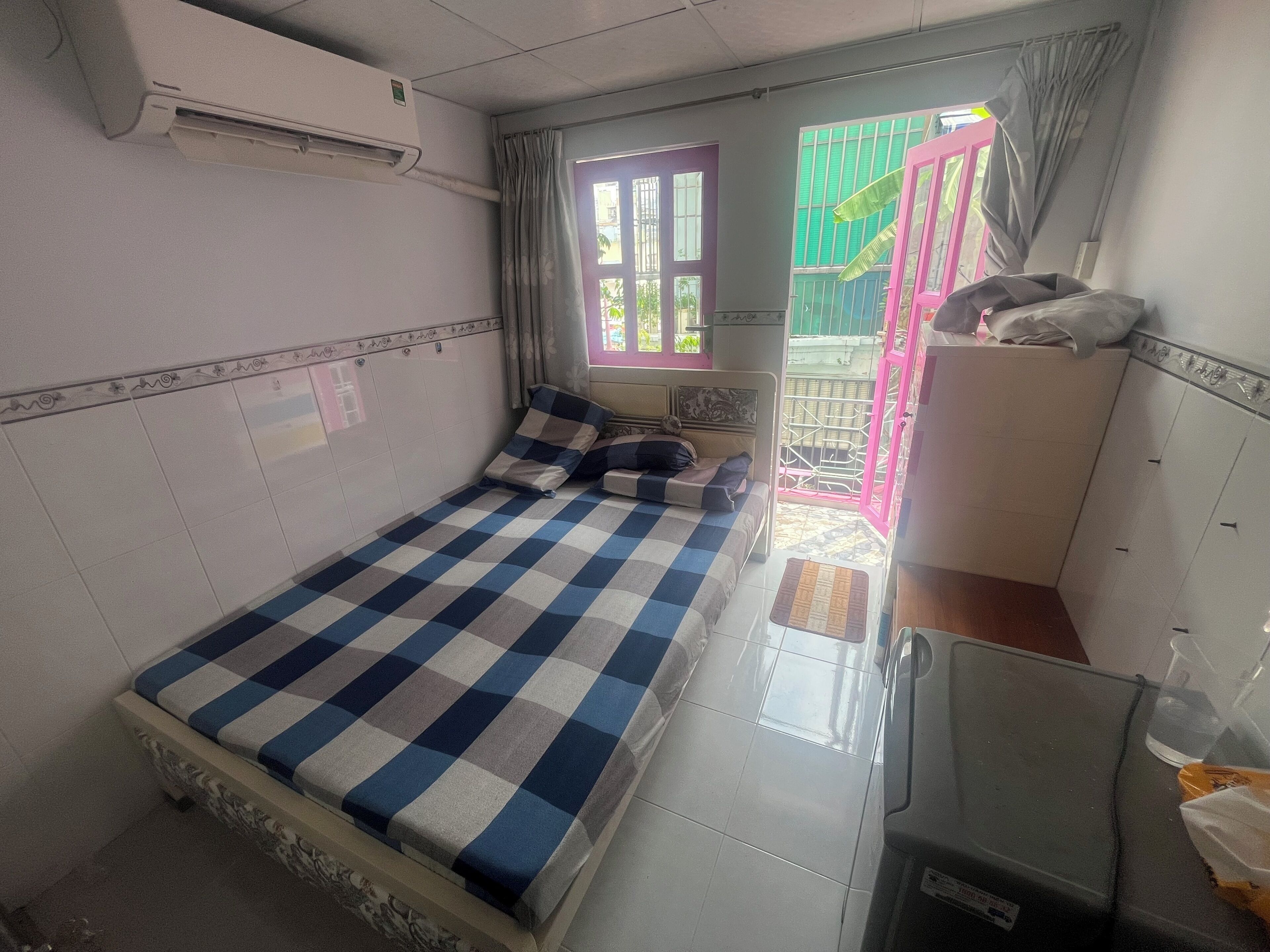 A room with a bed, a wardrobe, and an air conditioning unit.