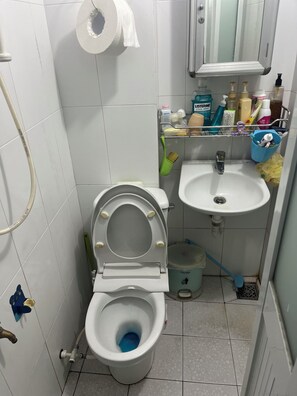 Un baño pequeño con inodoro, lavabo y distintos artículos de aseo.