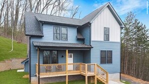 A two-story house with a covered porch and a wooden deck.