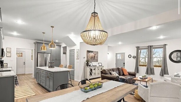 A modern kitchen with grey cabinets, a central island, and pendant lighting.