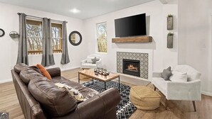 A modern living room with a fireplace, a flat-screen TV, and a comfortable seating area.
