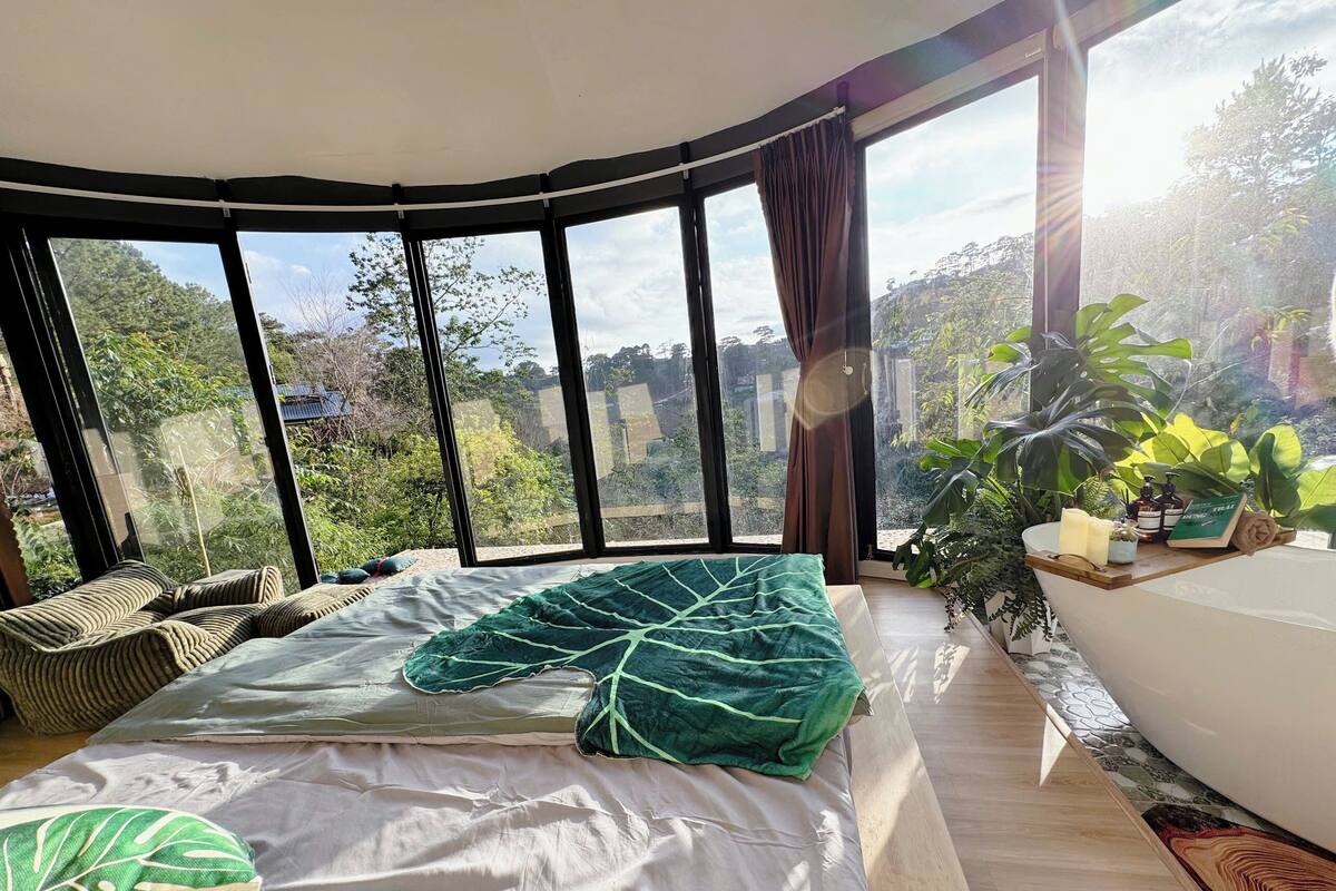 Une chambre avec un grand lit, une vue sur l’extérieur et une petite table avec des articles de toilette.