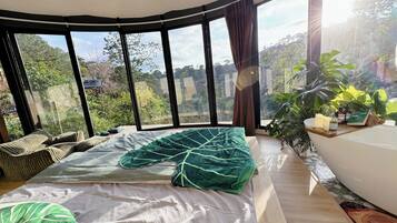 Un dormitorio con una cama grande, vistas al exterior y una pequeña mesa con artículos de aseo.