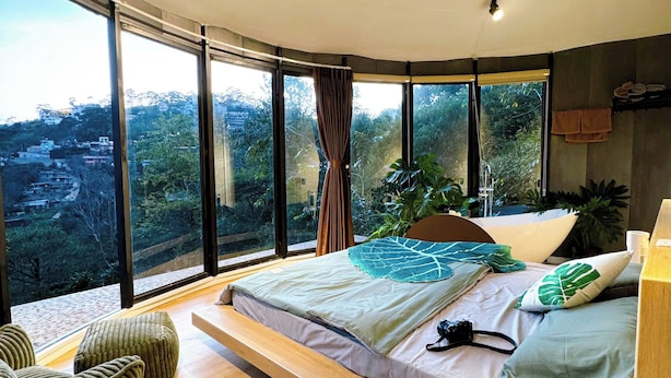 A bedroom with a large bed, a view of the city, and a wooden floor. - Dong Homestay  (Xuan Huong - Da Lat)