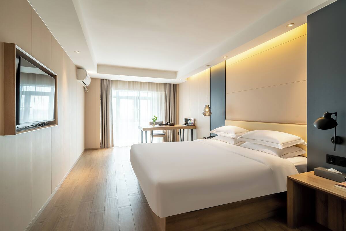 Una habitación de hotel moderna con una cama grande, un escritorio y un televisor.