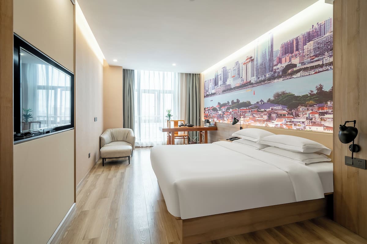 Un hotel moderno con una cama grande, un escritorio y un mural con vistas a la ciudad.