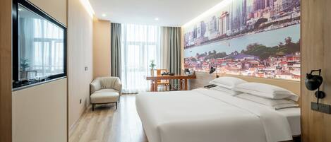 A modern hotel room with a large bed, a desk, and a cityscape mural on the wall.