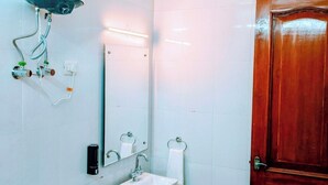 A bathroom with a toilet, sink, mirror, towel rack, and a wooden door. - Tulip Residency (Gurugram)