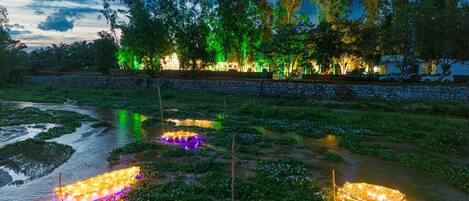 A nighttime view of a riverside area with illuminated structures and trees.