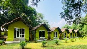 Une rangée de charmantes maisons aux toits végétalisés et aux grandes fenêtres, entourées d’une végétation luxuriante et d’arbres.