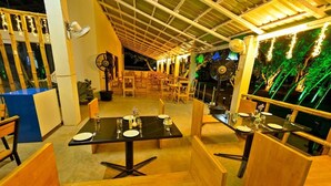 Un restaurant avec des banquettes et des tables en bois, dont certaines sont dressées avec de la vaisselle et des verres.