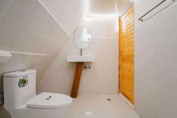 A small bathroom with a toilet, a wooden shower enclosure, and a white sink with a mirror. - LOUVREFER (Mae Taeng)