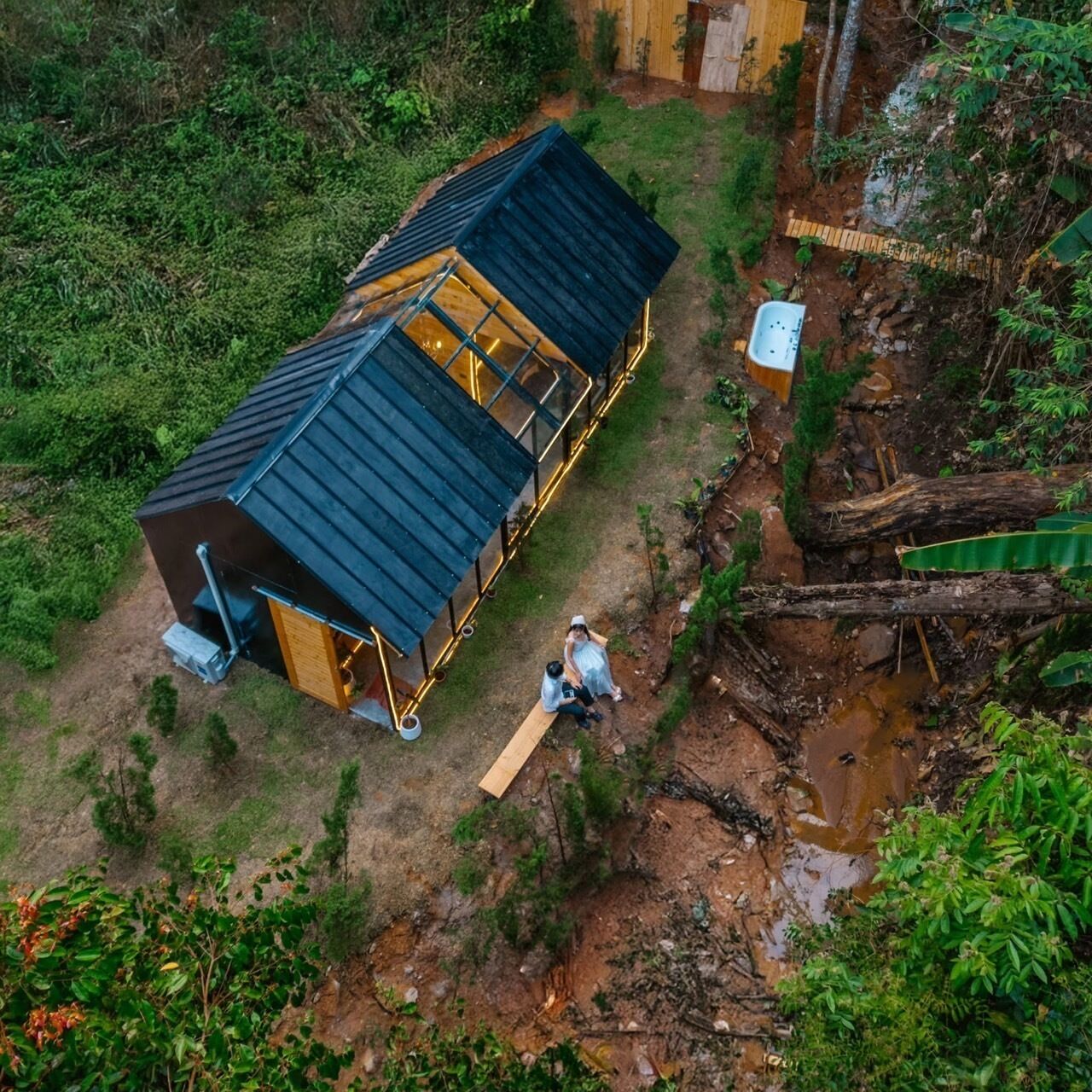 A two-story wooden cabin with a metal roof, surrounded by a natural landscape.