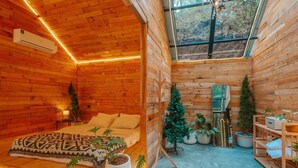 A cozy wooden cabin with a bed, potted plants, and a skylight. - LOUVREFER (Mae Taeng)