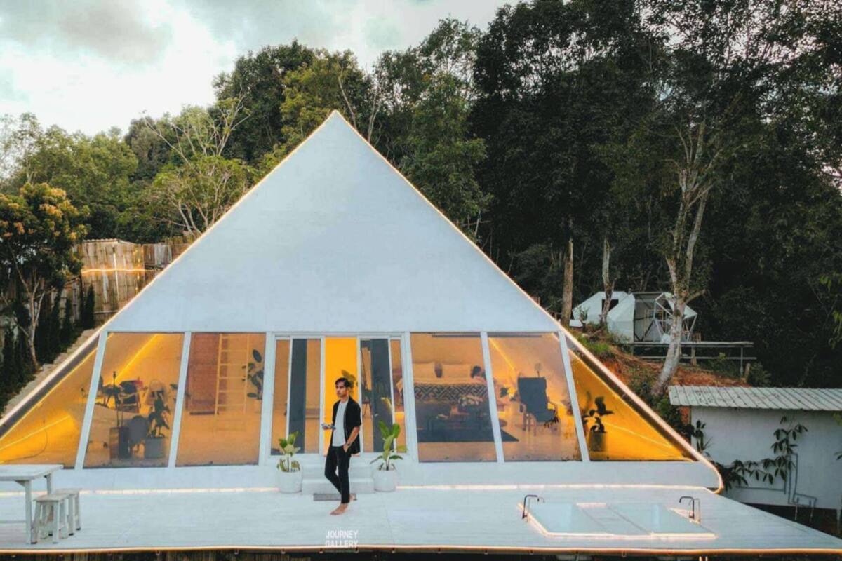A triangular glass structure with a person standing in front.