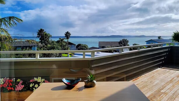 A balcony with a view of the sea, a wooden table, and a railing.