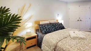 A bedroom with a bed, bedside tables, a lamp, a plant, and a wardrobe.