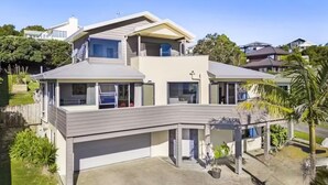 A modern two-story house with a flat roof, large windows, and a covered patio area.
