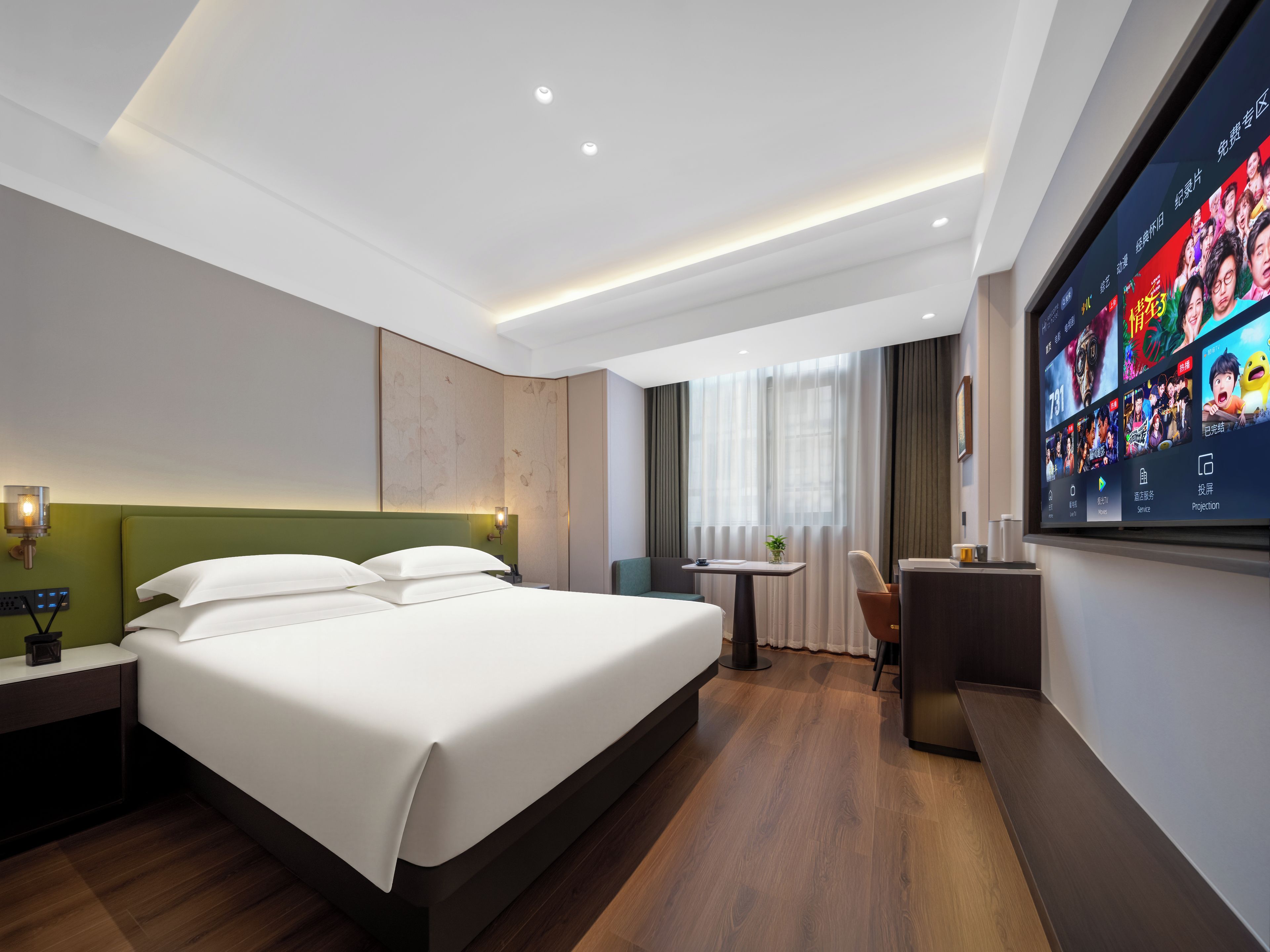Een hotelkamer met een groot bed, een bureau, een stoel en een televisie waarop films worden getoond.