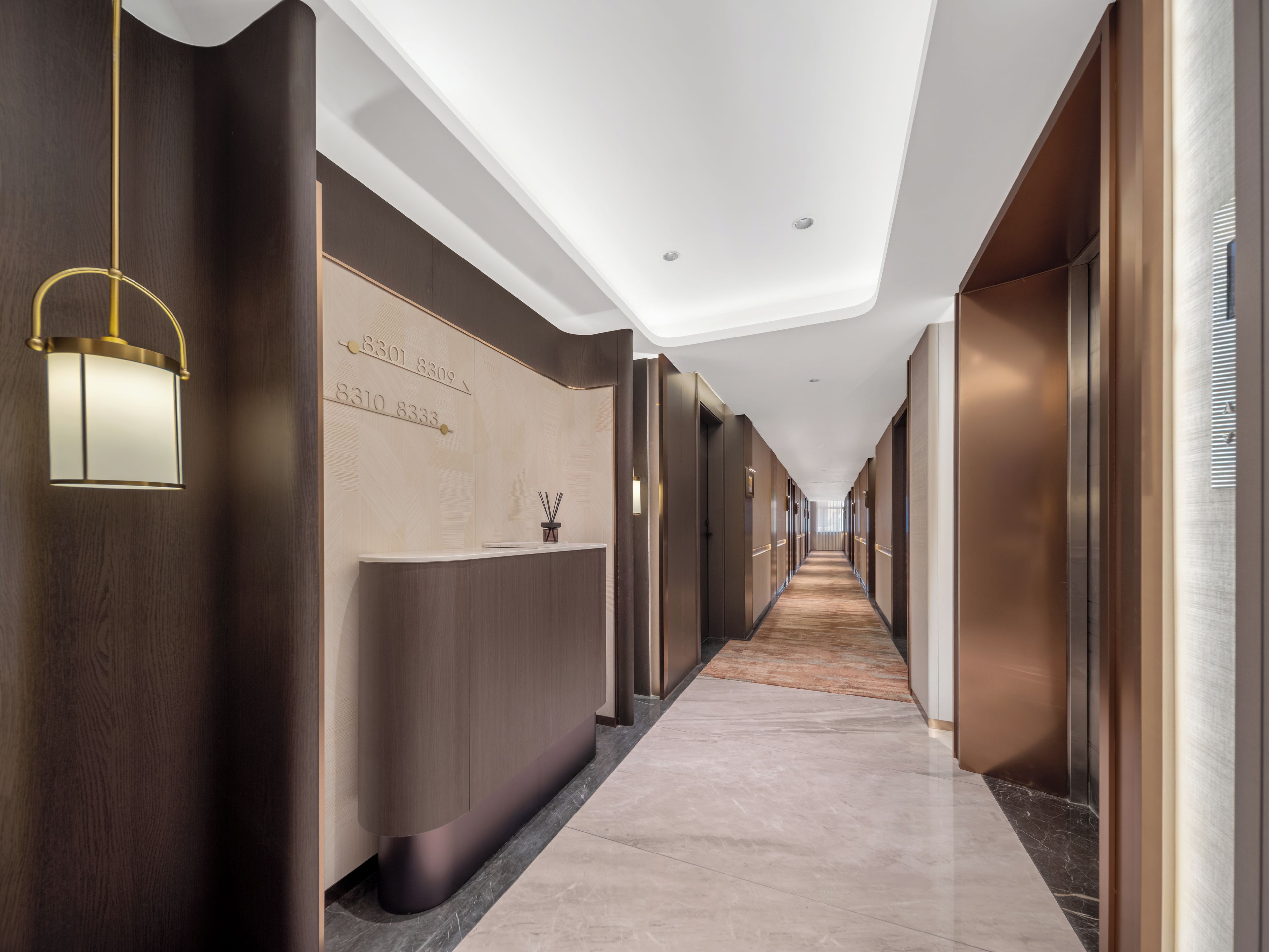 Et hotellets receptionområde med en lang gang, reception og en væg med værelsesnumre.