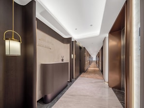 A hotel reception area with a long corridor, reception desk, and a wall with room numbers. - YIWU RUIFENG HOTEL (Jinhua)
