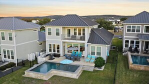 Une maison à deux étages avec un jardin comprenant une piscine, un espace salon extérieur et une zone délimitée par une clôture.