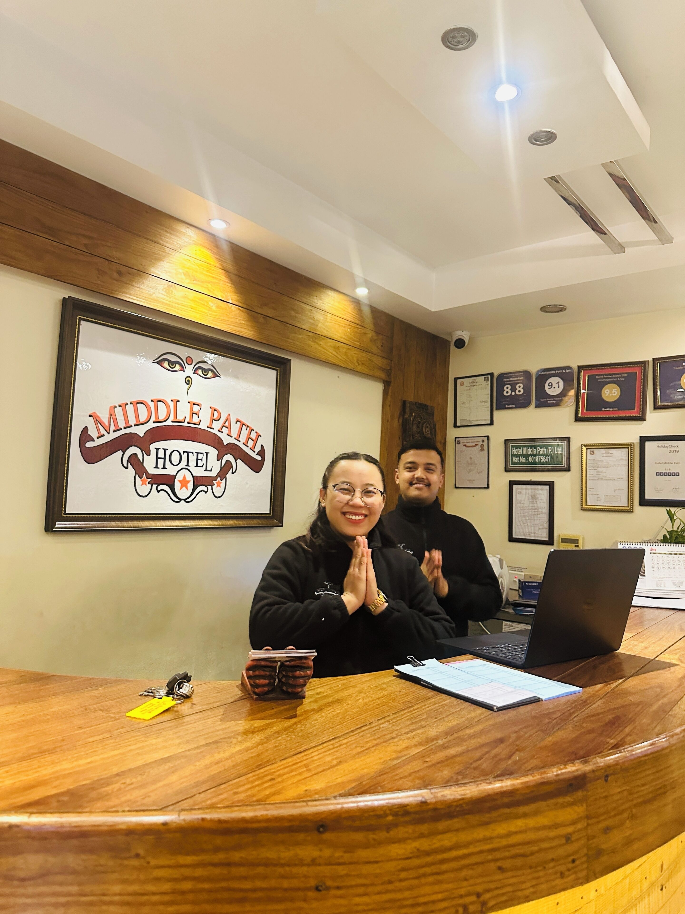 Un comptoir d’accueil à l’hôtel Middle Path, avec des récompenses et des certificats encadrés accrochés au mur.