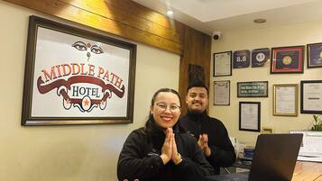 A reception desk at the Middle Path Hotel with framed awards and certificates on the wall.
