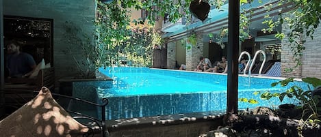 A pool area with a pergola, seating, and hanging planters.