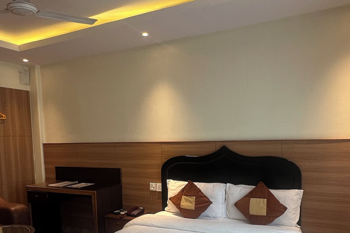 A hotel room with a bed, bedside table, lamp, and a ceiling fan.