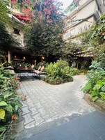 Un patio con sendero empedrado, zona de estar y abundante vegetación.