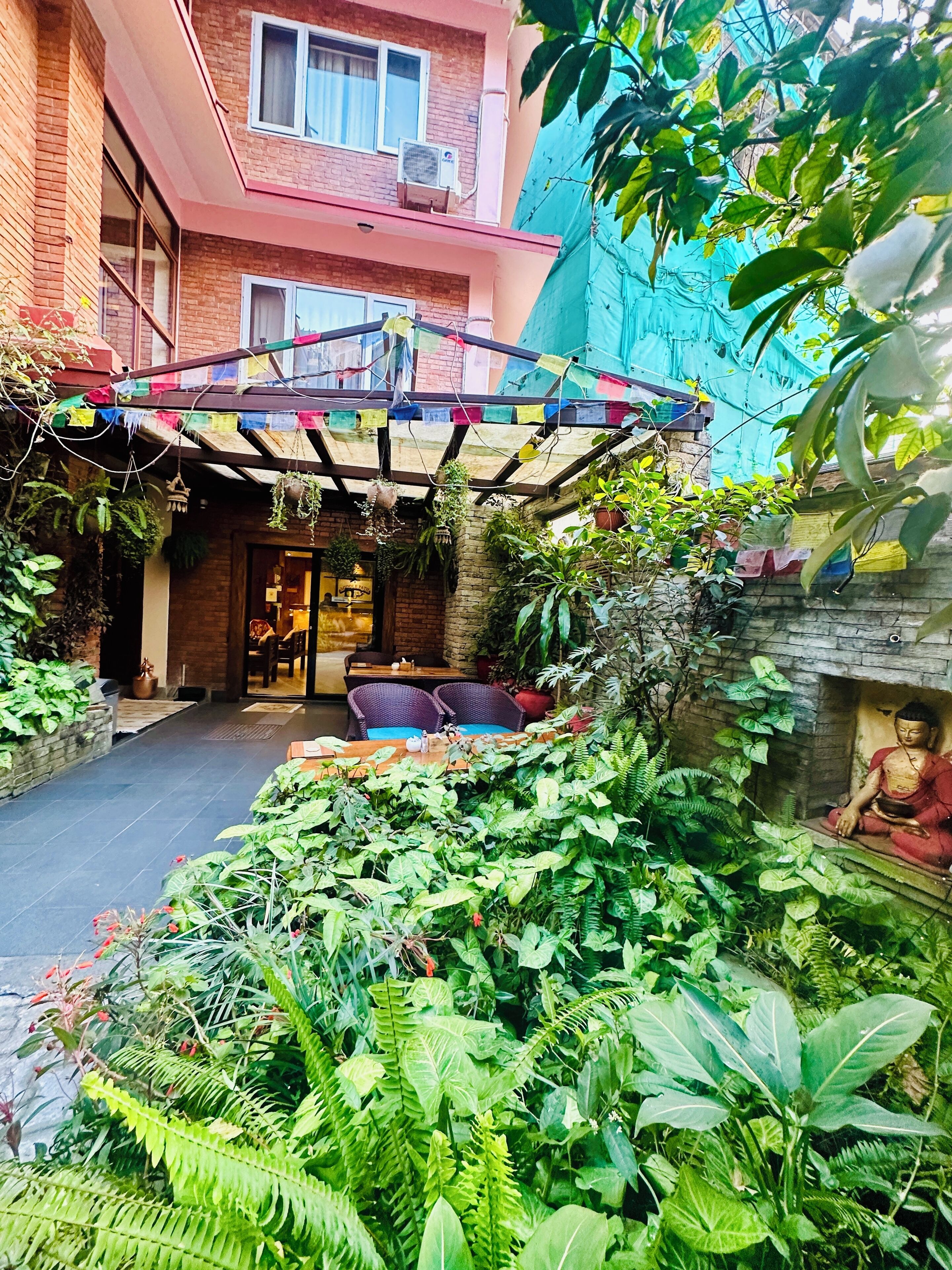 A courtyard with a covered seating area, potted plants, and a statue.