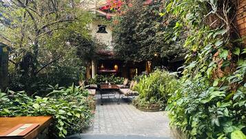 Un patio con un sendero pavimentado, un banco de madera y una mesa.